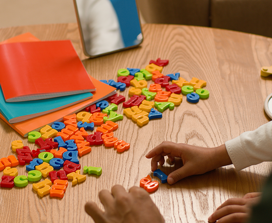 A child works on spelling words with block letters